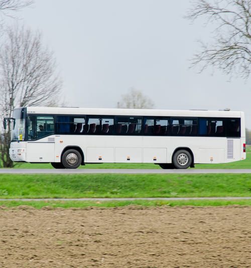 biały autobus Żana jadący po ulicy w lewą stronę