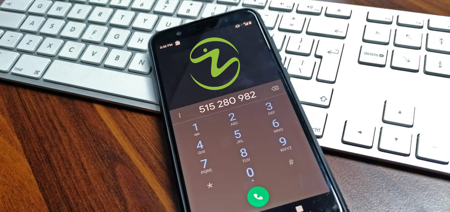 telefon leżący na biurku i białej klawiaturze, na ekranie telefonu widoczne logo Żany i wybrany do niej numer